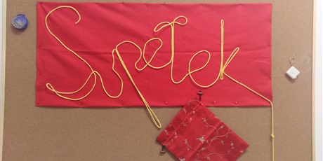 Powiększ grafikę: Napis Spełek ułozny ze sznurka przypięty na czerwonej tkaninie